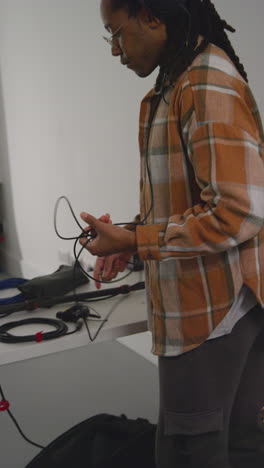 video vertical de un hombre grabando sonido de una película con auriculares comprobando el equipo grabando una película o un video en un estudio