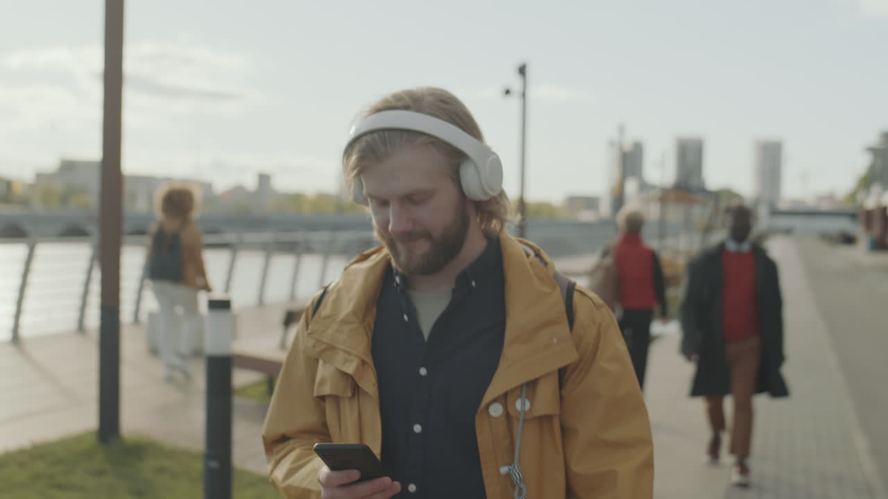 Man Walking in City and Listening to Music with Headphones