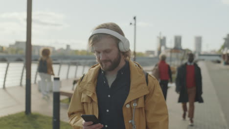 man walking in city and listening to music with headphones