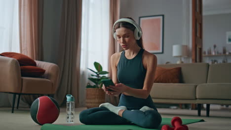 headphones girl practicing yoga meditation on sport mat home. peaceful woman