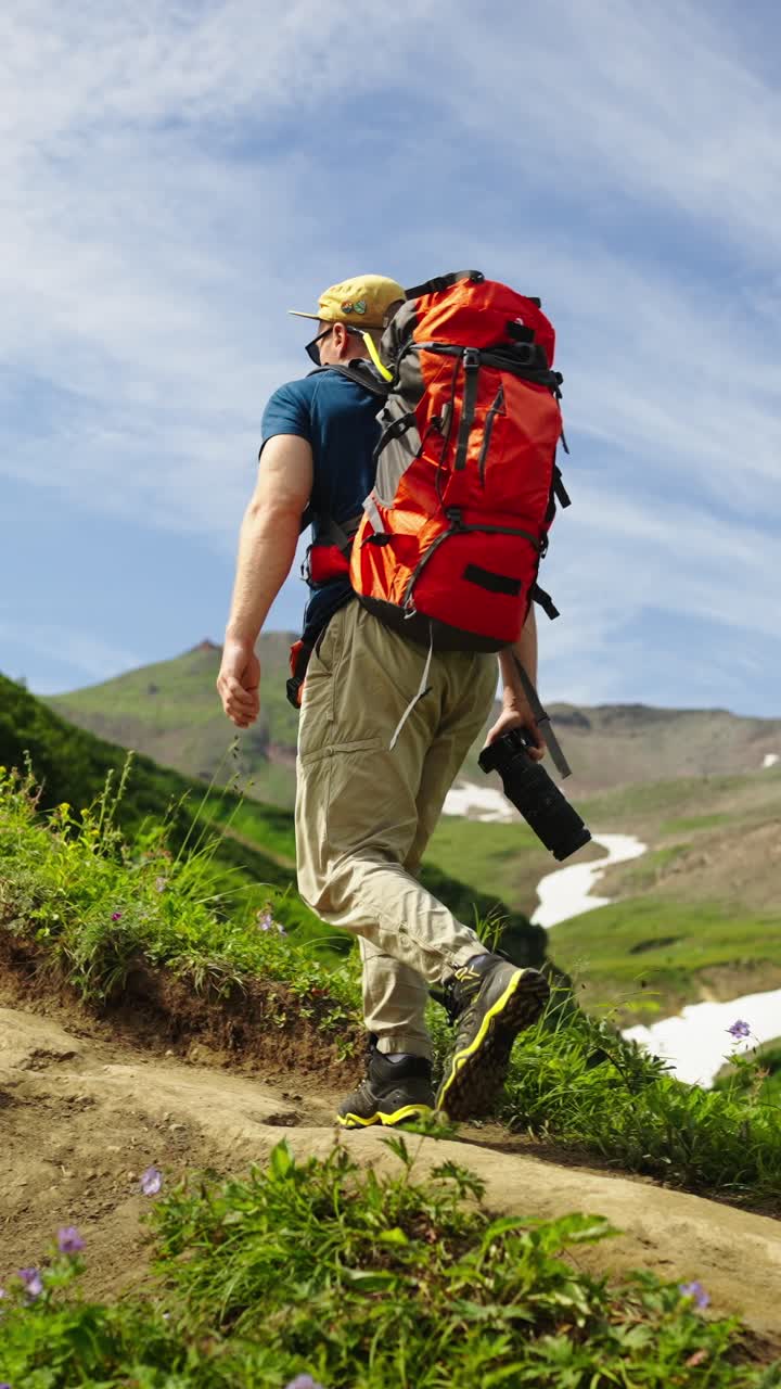 Un uomo e un gruppo in escursione in salita su un sentiero di montagna con zaini