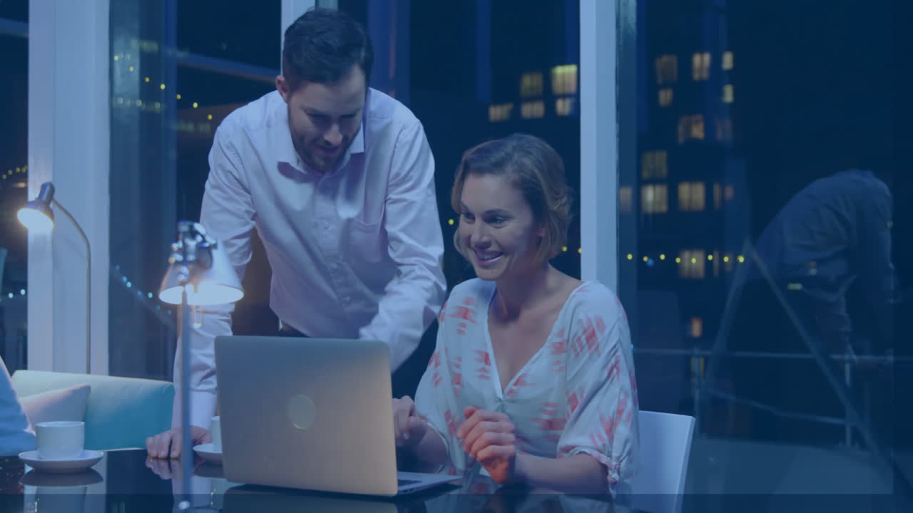 Collaborating on laptop, man and woman working in office with city lights