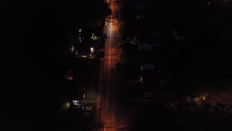 orange lighting lantern on street with driving car. aerial top down shot. american suburb area at midnight. vehicles driving alone on straight road in usa.