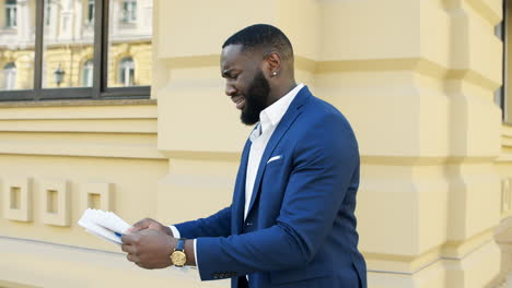 un homme d'affaires afro-américain lisant des documents à l'extérieur.