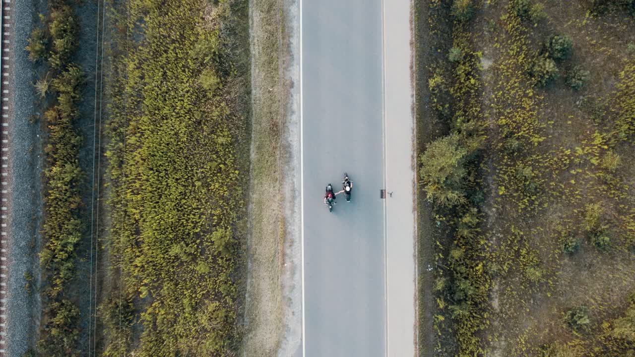 도로에서 하이파이브를 하는 두 명의 모터바이커의 공중 샷