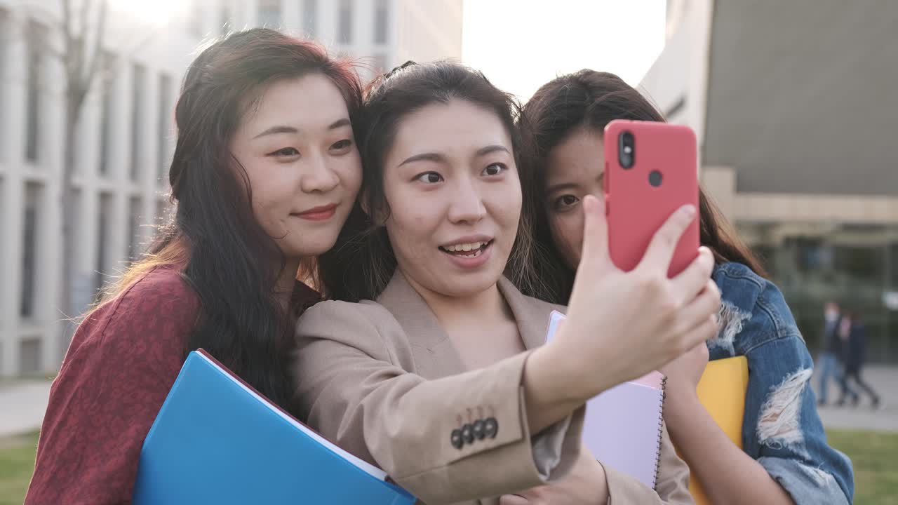 Group of female friends taking a selfie together with a mobile phone. Friendship concept. Students on campus