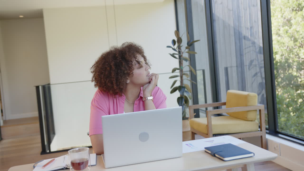 Working from home, woman sitting at desk with laptop and thinking