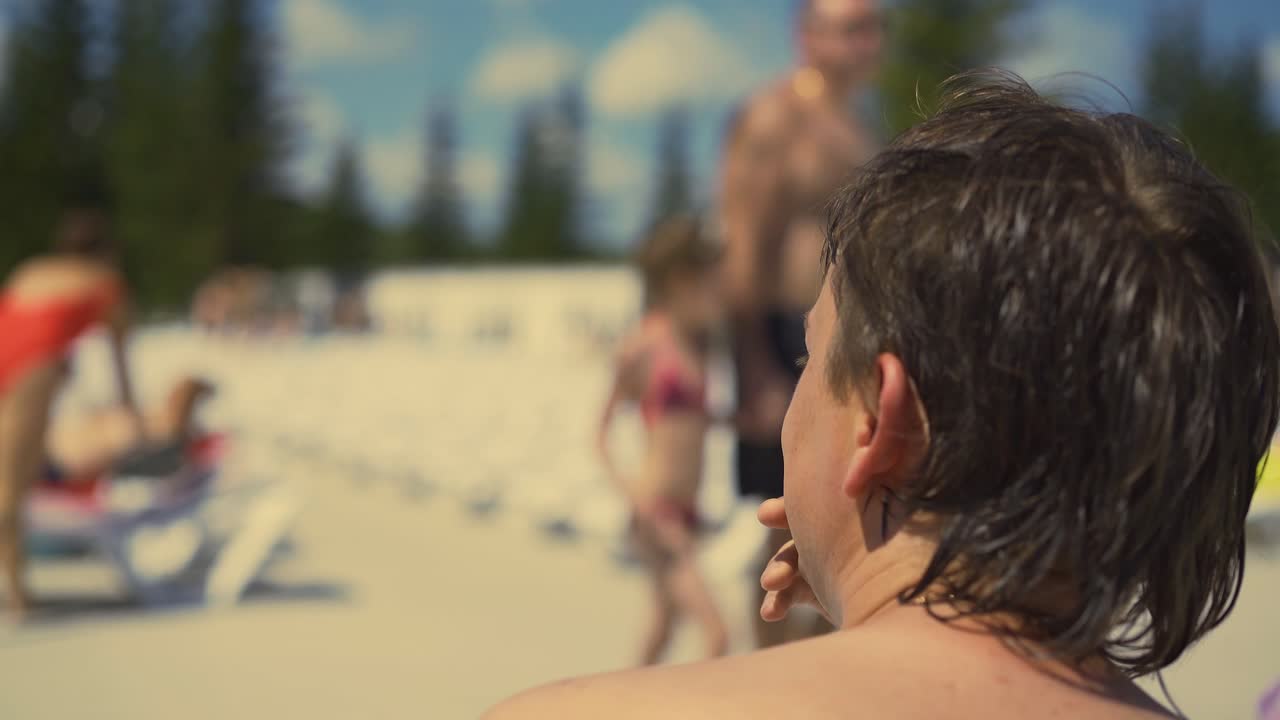 뒷면 가까운 젊은이가 해변에 앉아 있다