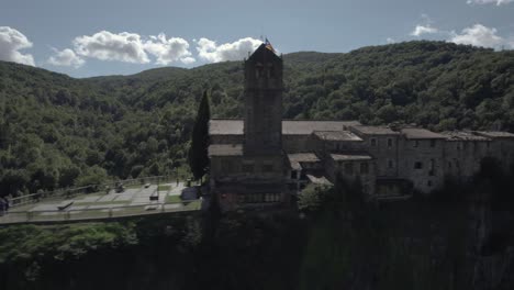 Das-Panoramavideo-Der-Drohne-Zeigt-Die-Atemberaubende-Schönheit-Von-Castellfollit-De-La-Roca,-Spanien:-Ein-Mittelalterliches-Dorf-Auf-Einer-Markanten-Vulkanklippe