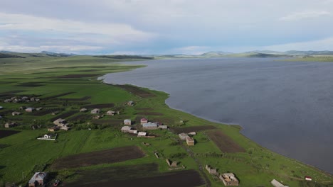 aerial shot of a lake surrounded by meadows villages old houses mountains