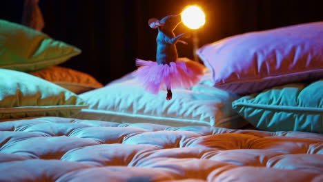 a mouse in a pink tutu dancing on a bed