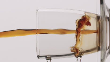 Close-up-shot-of-a-transparent-glass-getting-filled-with-brown-liquid-coffee-tea