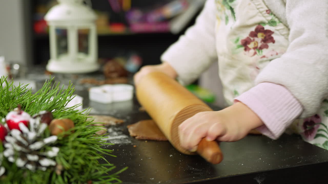Child rolls dough for gingerbread cookies in festive Christmas setting