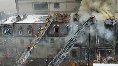 firefighters climbing the tower ladder to the top of an abandoned apartment building to help fight a fire