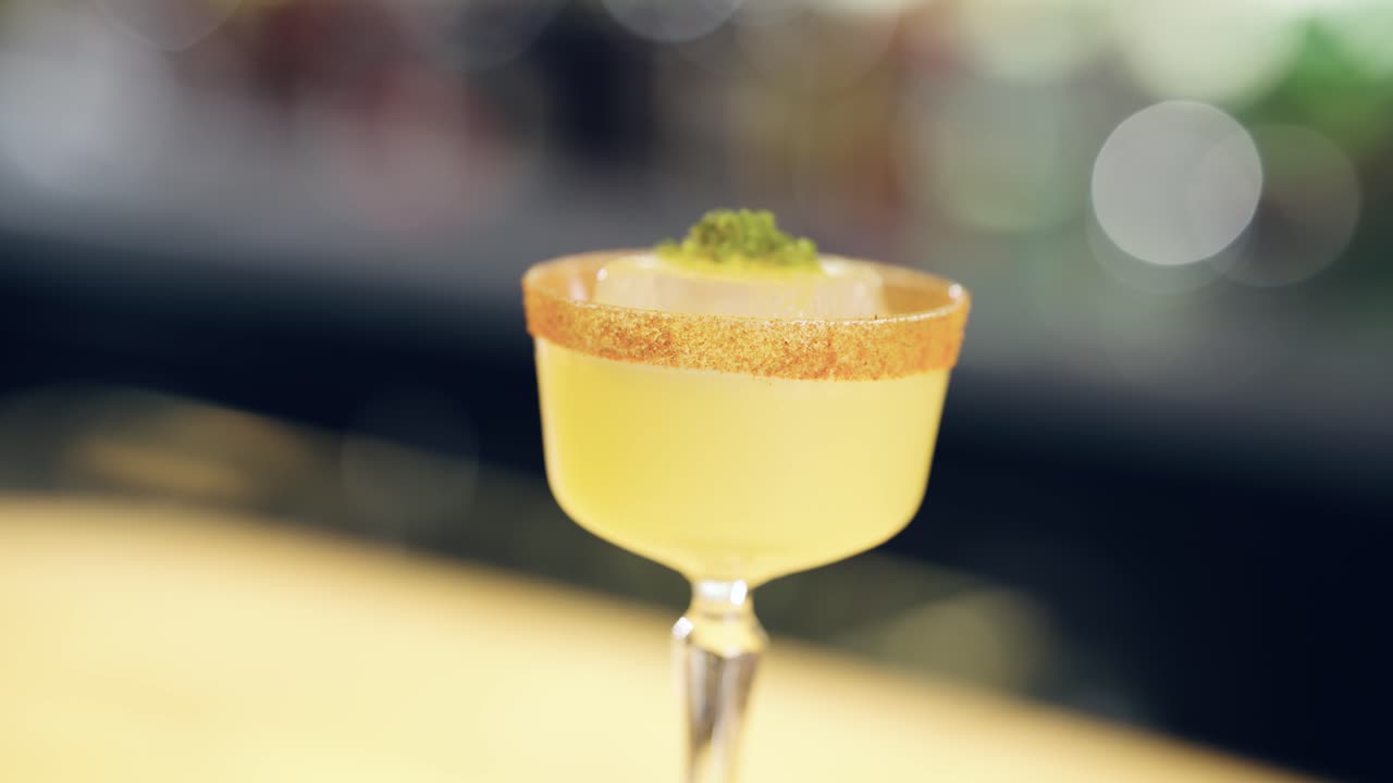 Primer plano de un elegante cóctel amarillo con guarnición en un bar