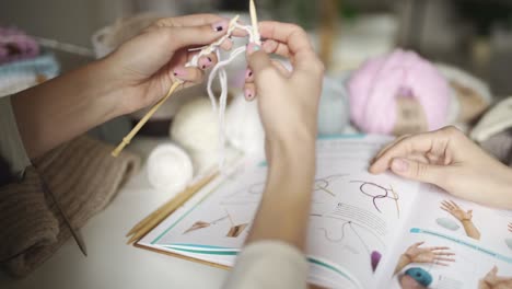 female hands learning to knit using knitting pattern. woman leisure