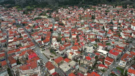 aerial flyover of kalambaka city with red rooftops and meteora rocks in the distance