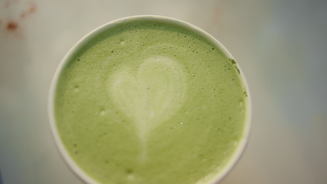 Vista de cima de um latte de matcha verde cremoso com textura de espuma.