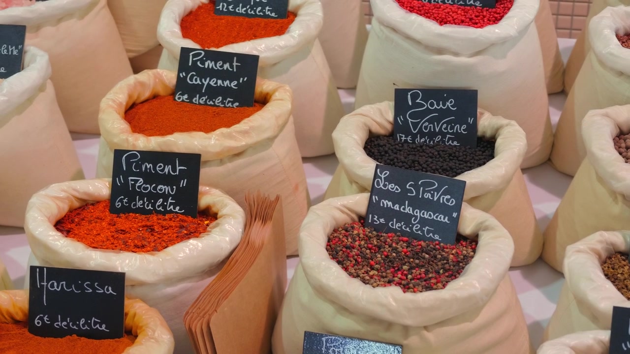 Wide view of many spice bags with handwritten French price labels at an outdoor market stall, Cannes, France