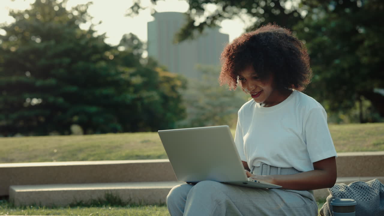 Young woman working on a laptop in a park
