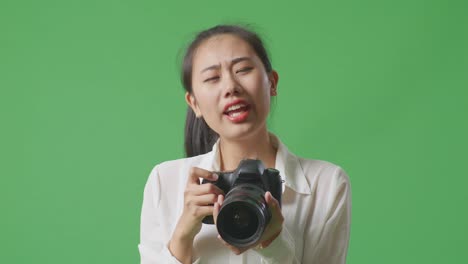 여성이 카메라를 들고 초록색 화면에서 악수하기 위해 손을 고 있습니다.