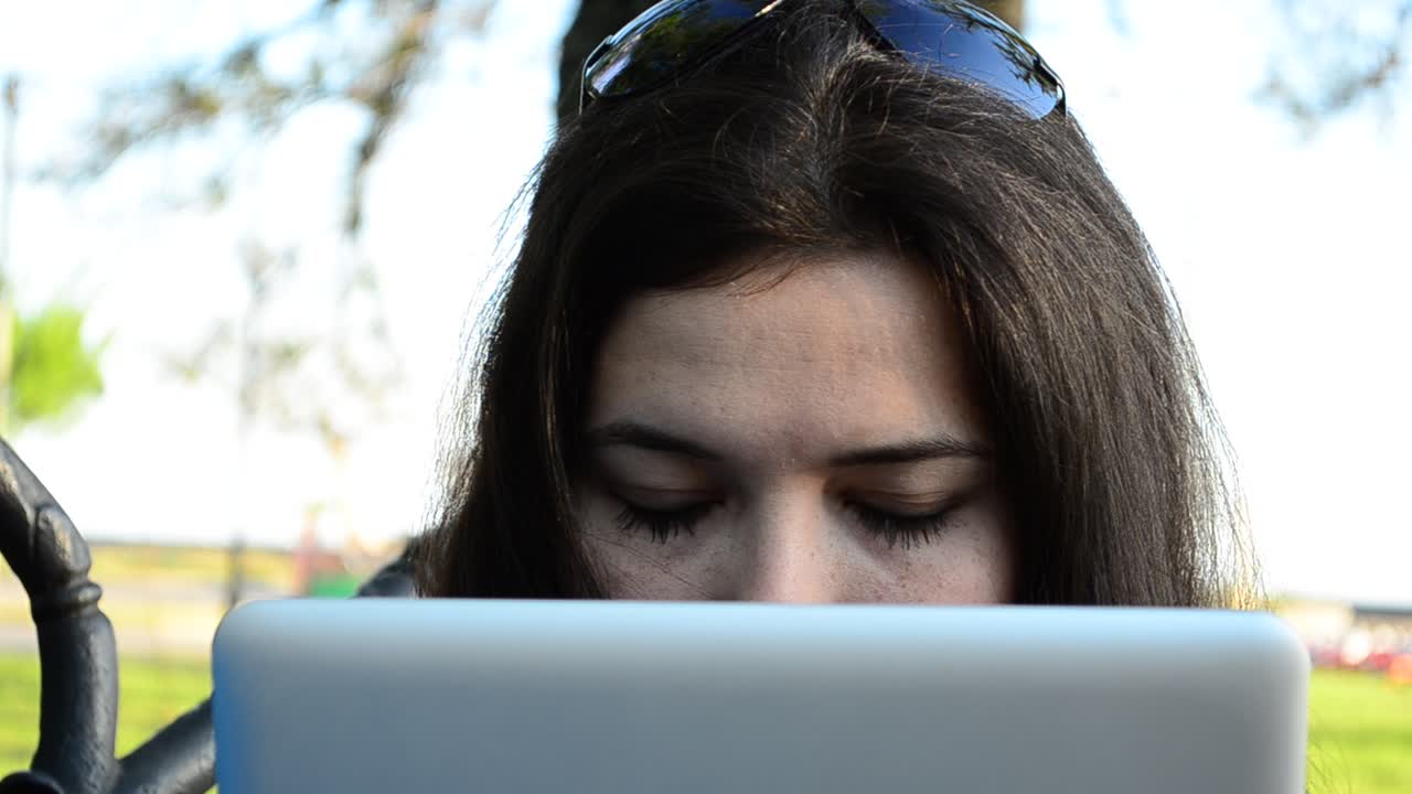La niña con la tablet en un banco. La chica de negocios trabaja con la tablet.