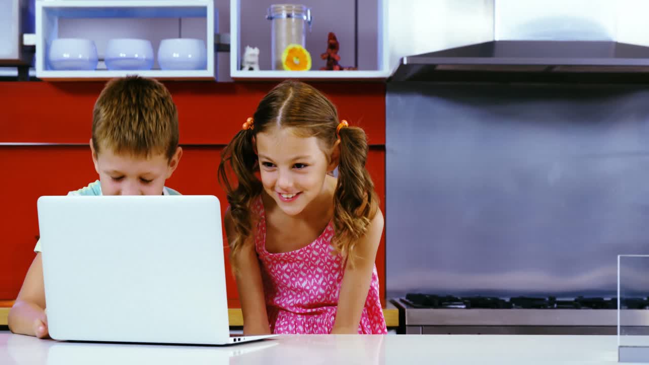 niños usando computadora portátil en la cocina