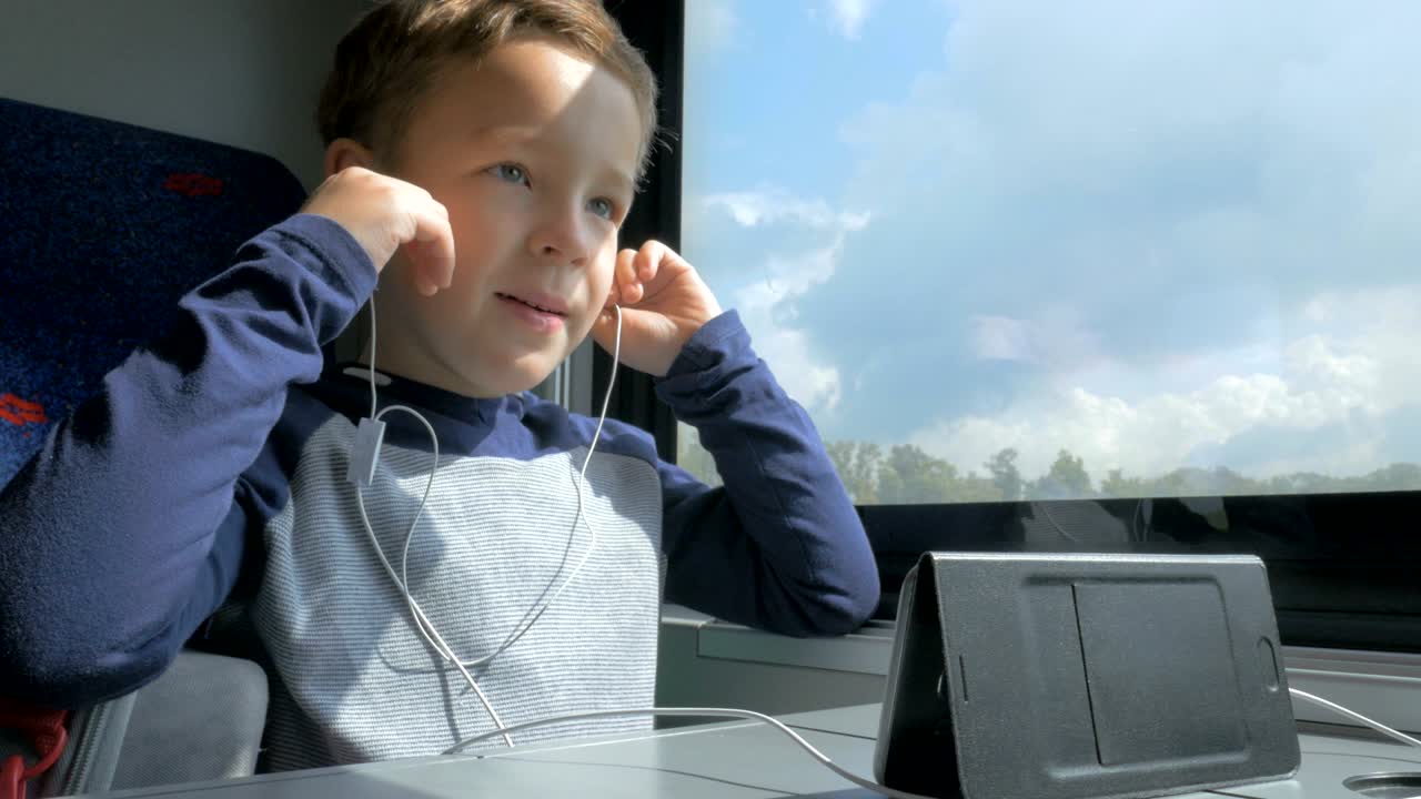 기차에서 아이가 휴대전화로 드프리 세트를 사용하고 있습니다.