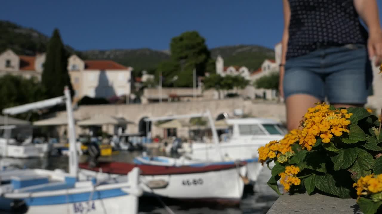 mujer caminando en el idílico paseo marítimo de la ciudad pasando por barcos, bol, croacia