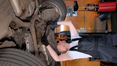 mechanic working underneath a car in an auto service center