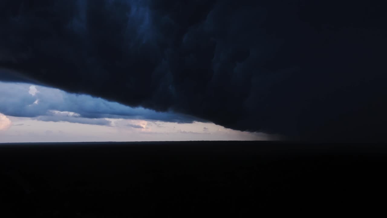 Dark clouds consume sky while distant rain reveals nature’s raw power and drama