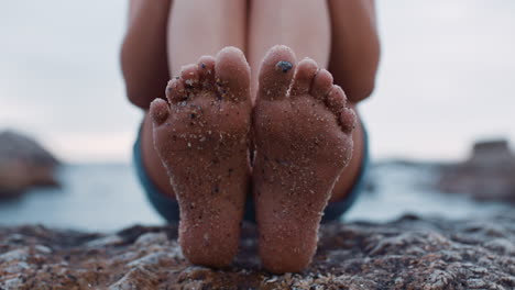 close up of sandy feet young woman sitting on beach barefoot enjoying summer vacation