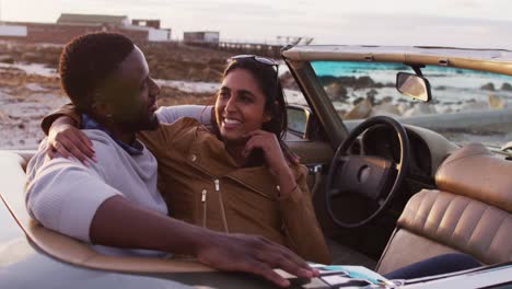 pareja afroamericana abrazándose mientras están sentados en el coche descapotable en la carretera