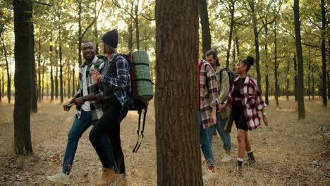 a happy group of people in plaid shirts and hiking clothes go on their small hike through the summer forest. multi-national group on a hike