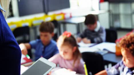 Teacher-using-digital-tablet-while-teaching-in-classroom