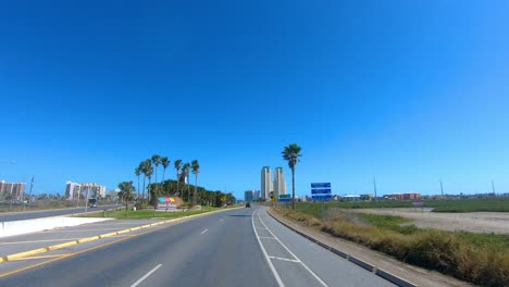 pov driving toward condo towers on south padre island and past marshy area along laguna madre on bright and sunny day in southern texas