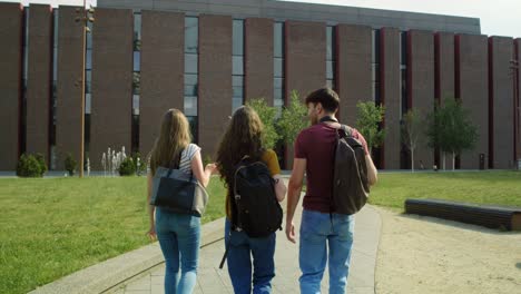 Rückansicht-Von-Drei-Kaukasischen-Studenten,-Die-Durch-Den-Universitätscampus-Laufen