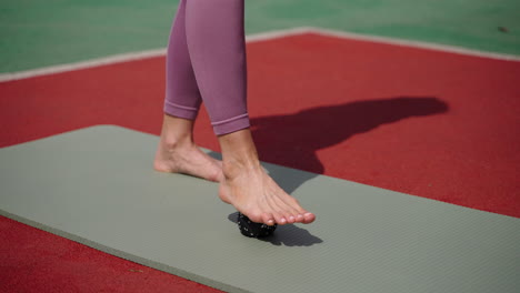 mujer haciendo ejercicio de masaje de pies en una alfombra de yoga