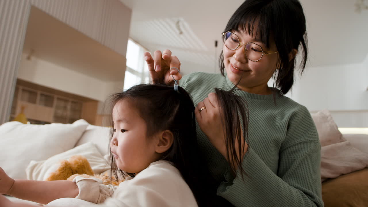 어머니 가 집 에서 딸 의 머리 를 꾸미고 있다