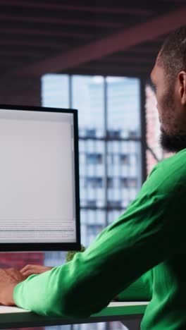 vertical video black it expert looking at user interface on computer at home office