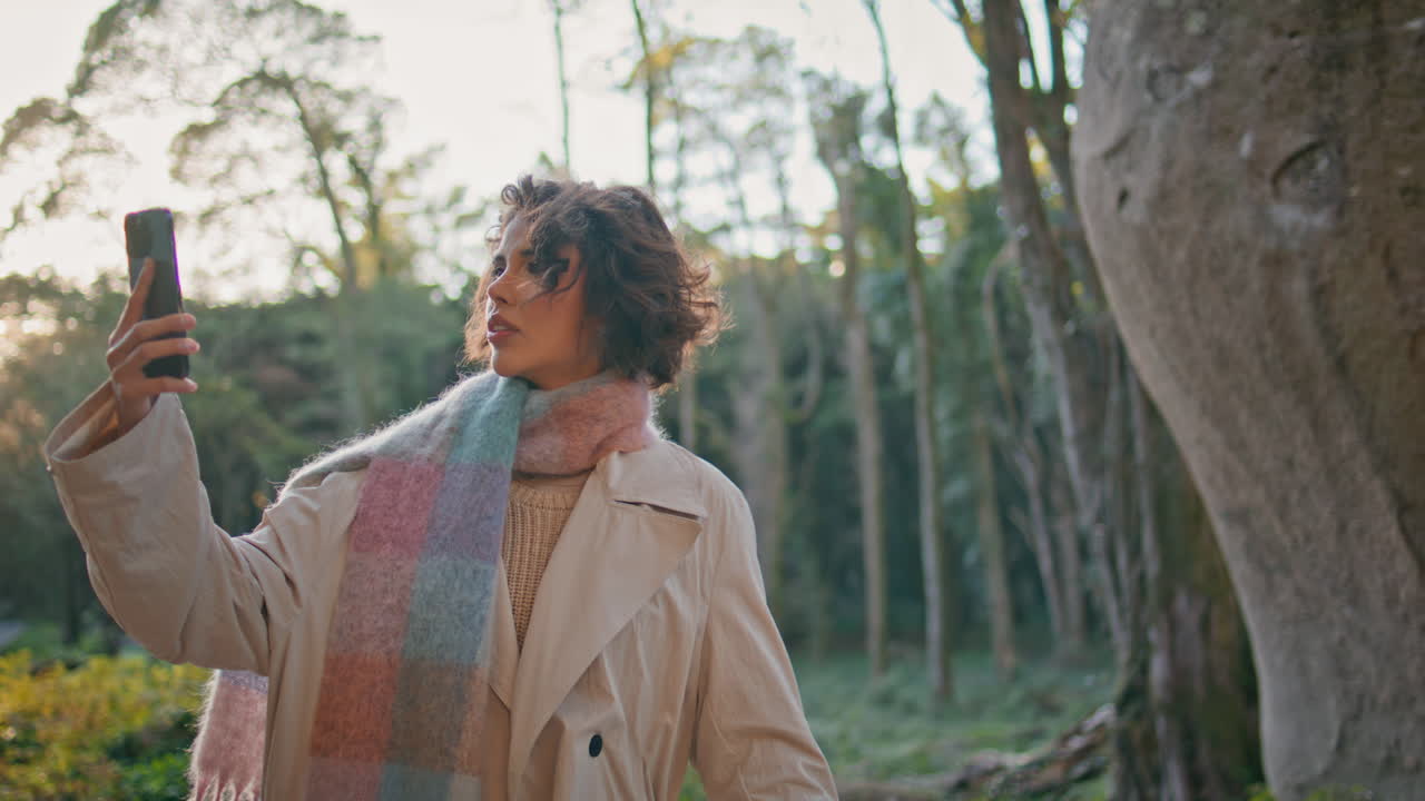숲에서 스마트폰 신호를 검색하는 여성은 캐주얼 가을 스타일의 클로즈업 옷을 입고 있습니다.