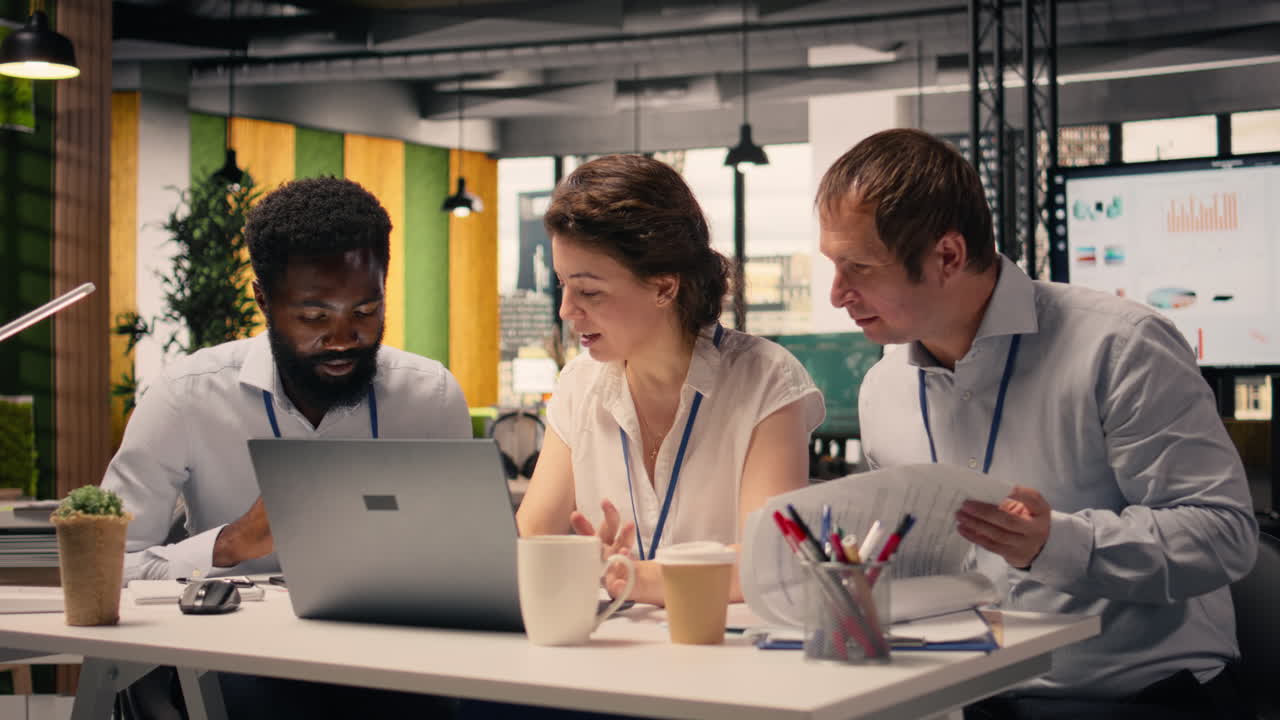 Team collaboration in a corporate office environment with laptop and reports