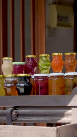 vibrant jars filled with a variety of homemade preserves are artistically arranged at a quaint market stall, basking in the warm sunlight and inviting passersby to stop and admire