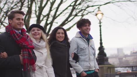 friends walking along south bank on winter visit to london