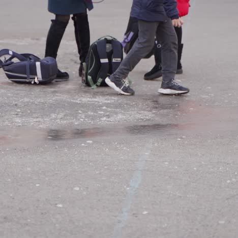close-up of children's feet. happy school kids slide on the ice in the schoolyard. frosty winter day.
