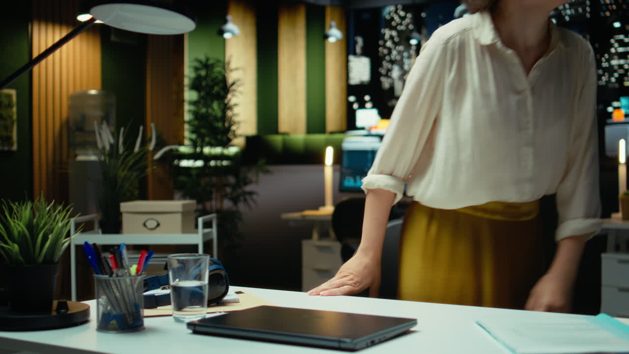 Vertical Video Overburdened woman prepares to leave office by turning off the lamp