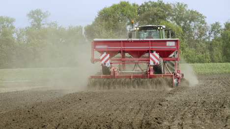 Farm-tractor-with-trailer-seeder-sowing-on-plowed-land.-Cultivated-field