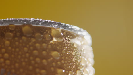 close up of condensation droplets on revolving takeaway can of cold beer or soft drink against yellow background with copy space 2