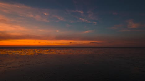 Zeitraffer-Des-Wattenmeeres-Bei-Schillig-In-Norddeutschland-Bei-Sonnenuntergang-Mit-Sich-Bewegenden-Wolken-Und-Spiegelung