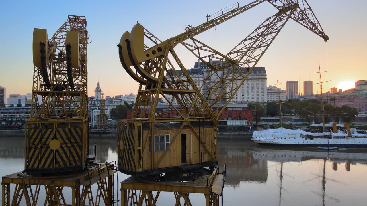 toma aérea orbitando alrededor de las antiguas grúas portuarias en la costanera de puerto madero al atardecer